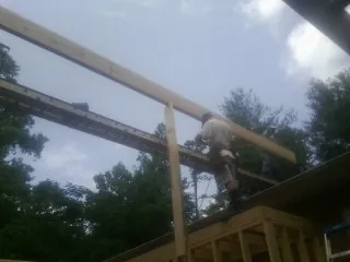 Carpenter setting a ridge beam over a new addition frame — Ice Dam Removal by Roofing Brothers in Poulan