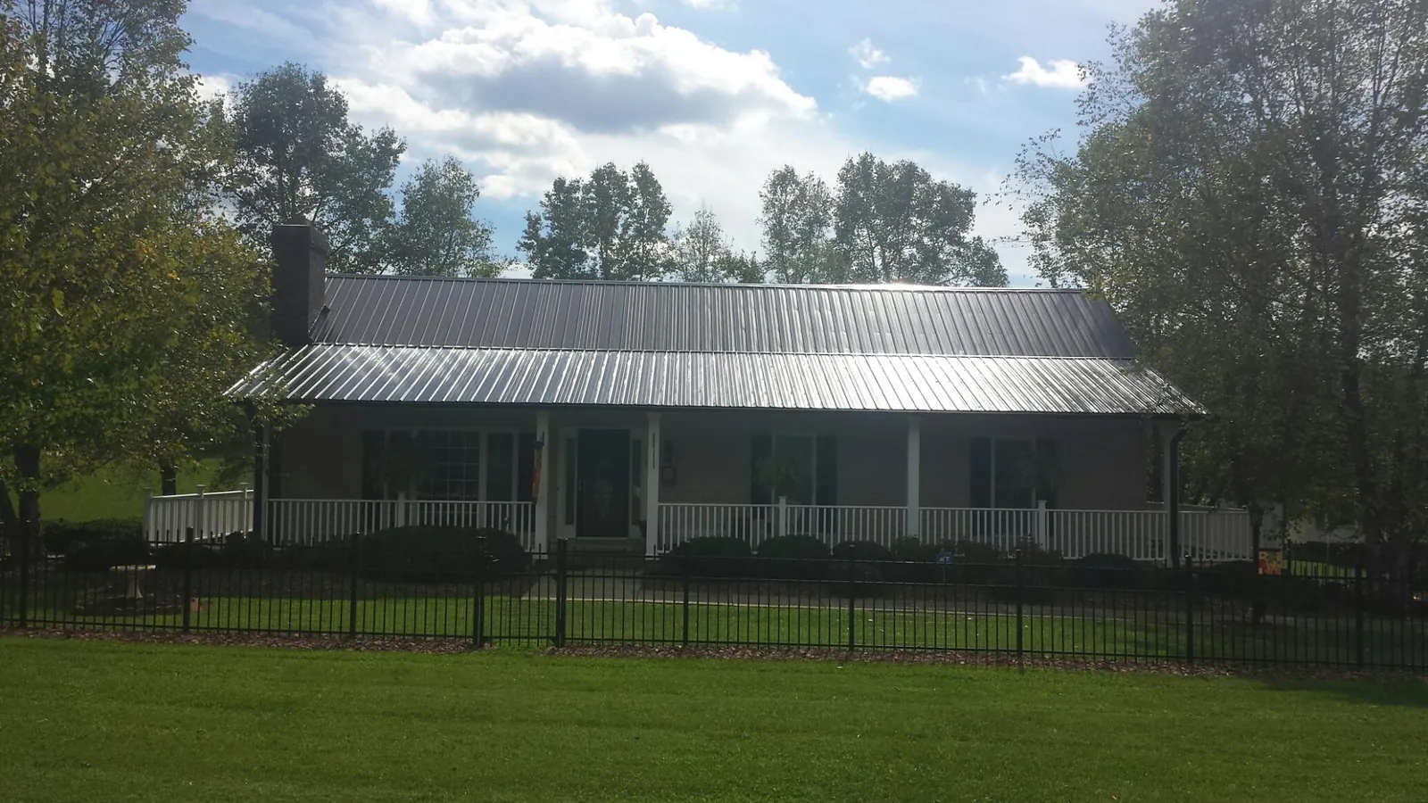 Gray metal roof on a brick ranch with a full width front porch — Gutter Guard Installation work by our crew in Poulan