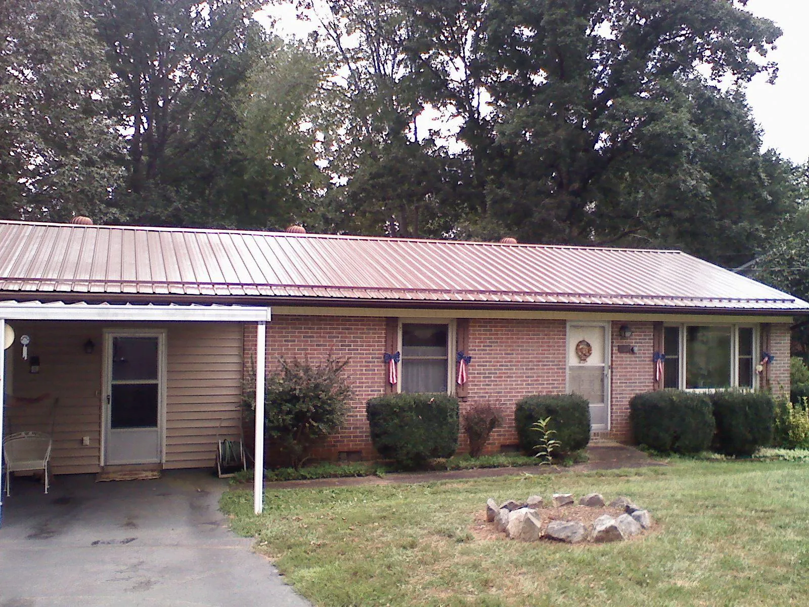 Bronze metal roof and carport on a brick ranch home — Roof Repair work by our crew in Poulan